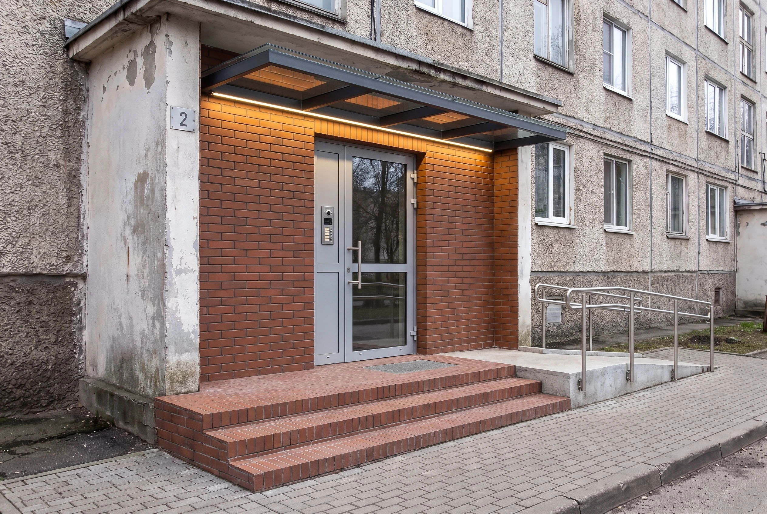 Та же входная зона после: клинкерная отделка, стеклянный козырёк, LED-освещение, пандус — AI-визуализация