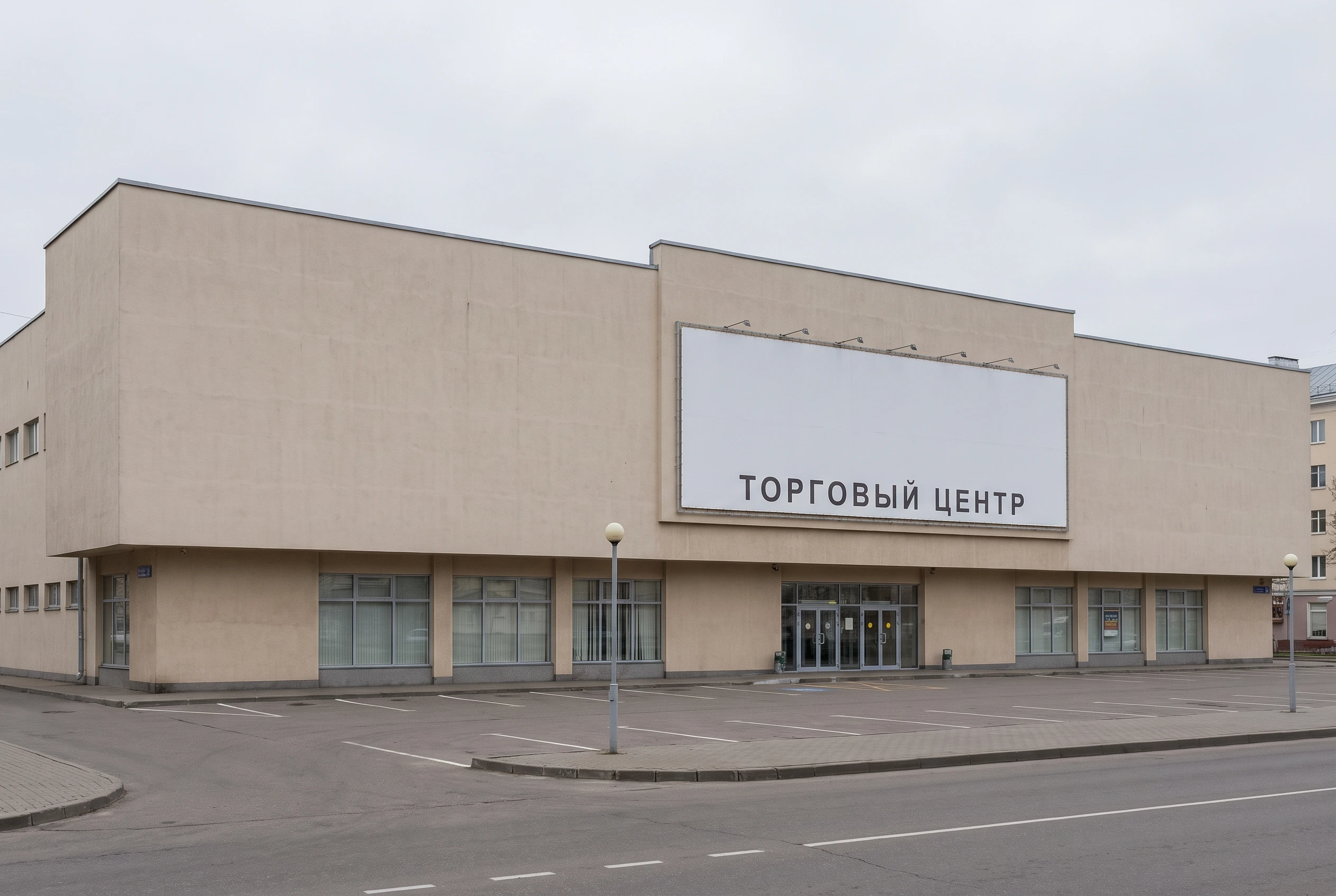 Типовой торговый центр 2000-х годов до реконструкции — плоская штукатурка, неосвещённая вывеска